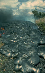 Toes of a pāhoehoe advance across a road in Kalapana on the east rift zone of Kīlauea Volcano in Hawaiʻi.
