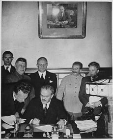 Molotov signs the Molotov-Ribbentrop Pact in Moscow. Behind him are Shaposhnikov, Ribbentrop, and Stalin.