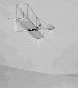 Wilbur Wright pilots the 1902 glider over the Kill Devil Hills, Oct 10, 1902. The single rear rudder is steerable; it replaced the original fixed double rudder.