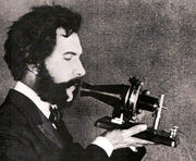 Bell speaking into prototype model of the telephone