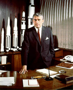Wernher von Braun stands at his desk in the Marshall Space Flight Center, Huntsville, Alabama in May 1964, with models of rockets developed and in progress.