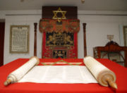 The Torah, or Jewish scripture. In the background are the Star of David and a Menorah, two important symbols of Judaism.