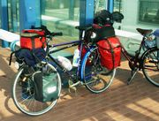 Touring bicycle equipped with head lamp, pump, rear rack, fenders/mud-guards, and numerous saddle-bags.