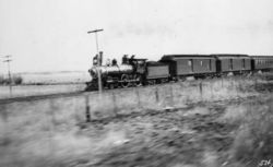 An Atchison, Topeka and Santa Fe Railway type 4-4-0 steam locomotive leads one of that railroad's passenger trains across Kansas circa 1895.