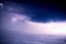 A view from the interior of Hurricane Betsy's eye.  In this photograph, taken by Hurricane Hunters on an aircraft in the middle of the eye, low clouds are seen covering the ocean in the foreground, with the eyewall looming miles high in the background.