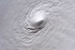 A picture of Hurricane Wilma's eye taken at 8:22 a.m. CDT October 19, 2005, by the crew aboard NASA's international space station, 222 miles above earth. At the time, Wilma was the strongest Atlantic hurricane in history, with winds near 185 mph (280 km/h) and a minimum central pressure of only 882 mbar.  Not only is this a classic example of a pinhole eye (the smallest ever observed—only 2 miles (3 km) across), but also of the stadium effect, where the eyewall slopes out and up.