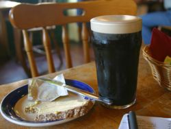 A "perfectly poured" Guinness pint with some brown bread.