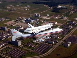 The space shuttle, atop its Boeing 747, flying over NASA's Johnson Space Center