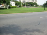 Looking in a southerly direction, with the white pergola and the knoll behind the photographer. The X on the street marks the position of the final head shot. Photo taken July, 2006.