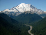 Mount Rainier with its main summit, Columbia Crest (14,410 feet) at the center. Massive Emmons Glacier covers most of the visible flank of the mountain. Left of the glacier is sharp pointed Little Tahoma (11,138 feet) with Frying Pan Glacier on its flank.