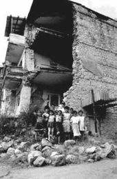 Children standing next to the rubble of a building in Stepanakert after a shelling barrage.