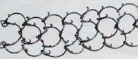 Closeup of a cilice-- a small metal chain with inwardly-pointing spikes