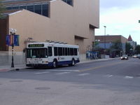 An AATA bus, with the blue-roofed Blake Transit Center in the background.