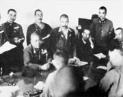 Lt Gen Yamashita (seated, centre) thumps the table with his fist to emphasise his demand for unconditional surrender. Lt Gen Percival sits between his officers, his clenched hand to his mouth (Photo from Imperial War Museum)