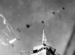A Japanese "Val" dive bomber is shot down by anti-aircraft fire directly over Enterprise.