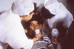 Nurses encouraging this patient to drink an Oral Rehydration Solution to improve dehydration he acquired from cholera.Courtesy:Centers for Disease Control and Prevention