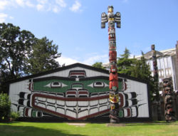 A Kwakwaka'wakw totem pole and traditional "big house" in Victoria, BC.