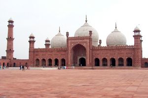 The Badshahi Masjid in Lahore, Pakistan with an iwan at center, three domes, and five visible minarets