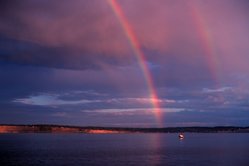 Primary and secondary rainbows are visible, as well as a reflected primary and a faintly visible reflection primary.