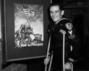 John Bradley, who temporarily needed crutches following the battle due to shrapnel injuries, appearing next to a poster for the 7th War bond drive
