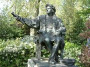 A bronze statue of Columbus sits among the flowers and trees of Belgrave Square, London.