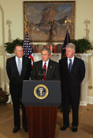 President George W. Bush talks about the Tsunami disaster in Indonesia as former Presidents Bill Clinton and George H.W. Bush look on.