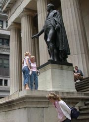Tourists pose under the statue of Washington outside the Federal Hall Memorial in lower Manhattan, site of Washington's first inauguration as President