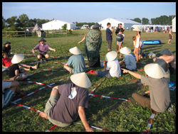 Go played using humans wearing hats (black or white) in place of stones (black or white) on a grid laid out in the grass.