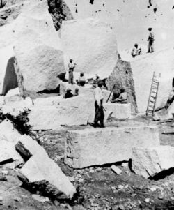 Quarrying granite for the Mormon Temple, Utah Territory. The ground is strewn with boulders and detached masses of granite, which have fallen from the walls of Little Cottonwood Canyon. The quarrying consists of splitting up the blocks.