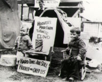 Children are sitting infront of signs criticizing Hoover's policies. One sign says "Hard Times Are Still Hoover-ing Over Us".