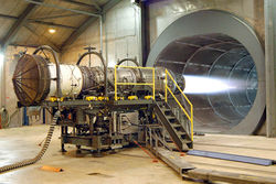 A Pratt & Whitney F100 turbofan engine for the F-15 Eagle is tested at Robins Air Force Base, Georgia, USA. The tunnel behind the engine muffles noise and allows exhaust to escape. The mesh cover at the front of the engine (left of photo) prevents foreign objects (including people) from being pulled into the engine by the huge volume of air rushing into the inlet.