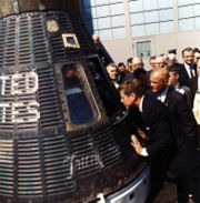 JFK looks at the space craft Friendship 7, the spacecraft which made three earth orbits, piloted by astronaut John Glenn.