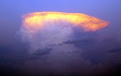 The setting sun illuminates the top of a classic anvil-shaped thunderstorm cloud, eastern Nebraska, United States.