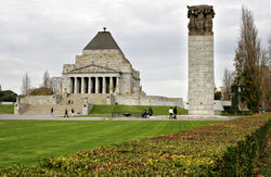 A view of the northern face of the Shrine showing many visitors paying their respects. The annual ANZAC Day parade approaches the Shrine from the north. This view shows the sculptures in the pediment, clearly inspired by those of the Parthenon. The central figure is the "Call to Arms.".