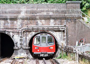 The nickname "the Tube" comes from the circular tube-like tunnels through which the small-profile trains travel. This photograph shows a southbound Northern Line train leaving a tunnel just north of Hendon Central station.