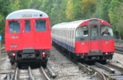 Underground trains come in two sizes, larger sub-surface trains and smaller tube trains. A Metropolitan Line A Stock train (left) passes a Piccadilly Line 1973 Stock train (right) in the siding at Rayners Lane