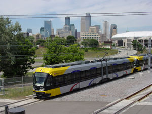 Metro Transit Hiawatha Line train approaching Cedar-Riverside Station. Downtown Minneapolis is in the background, Metrodome on the right.