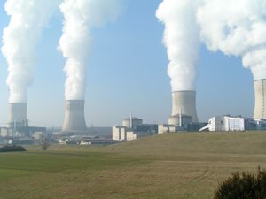 A nuclear power station. Fog rises from the hyperboloid shaped cooling towers. The nuclear reactors are inside the cylindrical containment buildings.